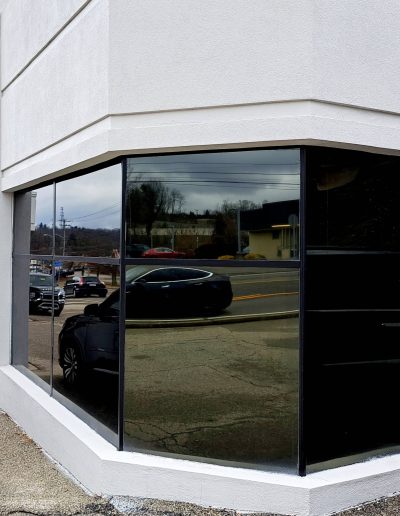 Exterior of commercial building with corner windows showing black car reflection