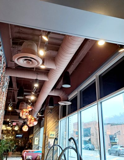 View of decorated commercial interior with exposed ductwork in ceiling and large rectangular windows
