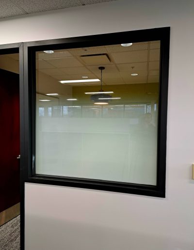 close-up view of large black framed square window with white frosted glass