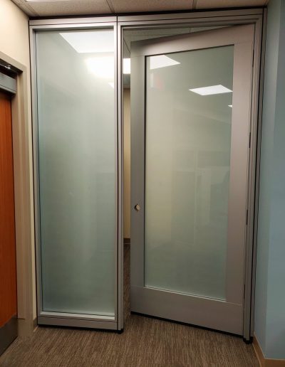 Glass door with grey framing and frosted glass in commercial hallway