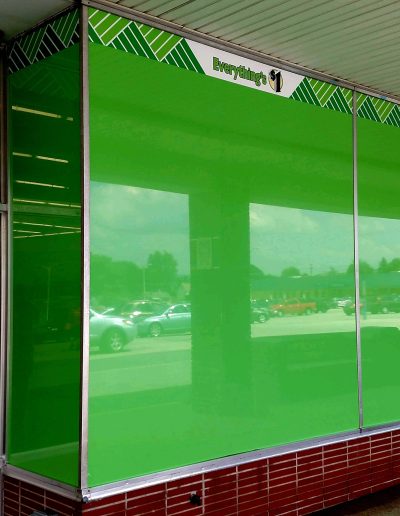Retail store exterior with brick foundation and glass windows with green advertising