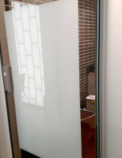 Interior glass office door with white etched rectangle in middle framed in metal