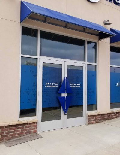 Outside view of Sleep Number retail store with blue logo on windows and glass door