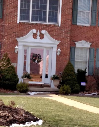 Large red brick house with large decorative white window over white decorative front door