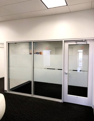 Interior office with dark grey carpet, white walls and windows with frosted glass in middle