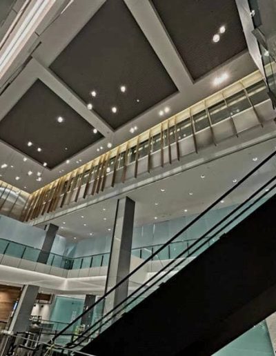 Upward view of interior of large two story commercial building with stairs, decorated walls and walkways framed with frosted glass panels