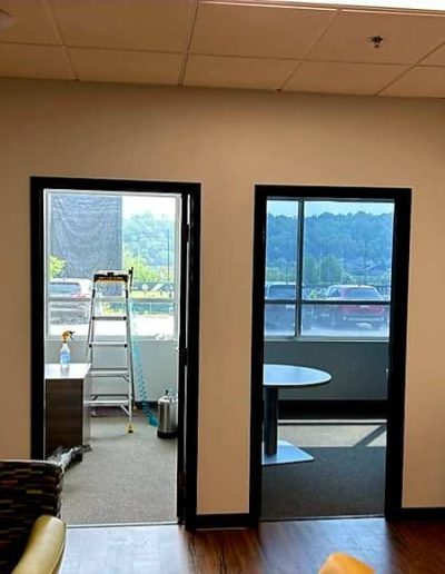 Office lobby with view of two separate office doors framed in black opening to offices with large windows