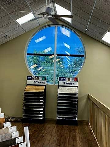 Interior view of flooring store with several samples on display under large round window divided with pointed ceiling